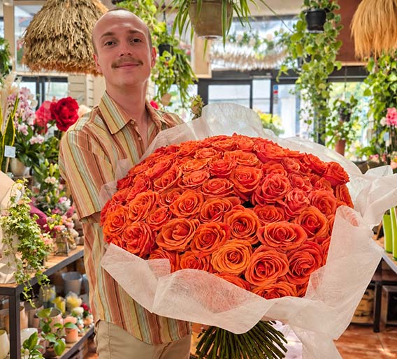 Imposant bouquet de roses orange présenté par un fleuriste dans la boutique Rosae à Hyères, création florale artisanale