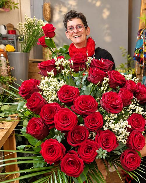 Sabrina, Maître Artisan fleuriste, avec un bouquet de roses rouges dans sa boutique de Hyères