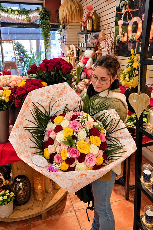 Justine, fleuriste chez Rosae à Hyères, tient un grand bouquet de roses multicolores prêt pour la livraison