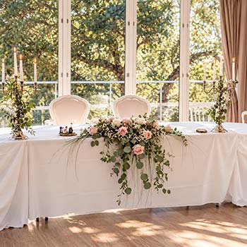 Centre de table de mariage aux roses pastel et feuillages retombants, création florale élégante de Rosae à Hyères.
